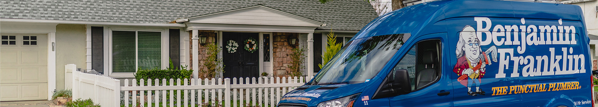 Benjamin Franklin Plumbing service van parked in front of a house.