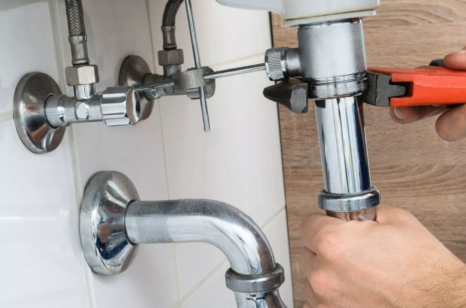 A plumber adjusting a water connection with a wrench