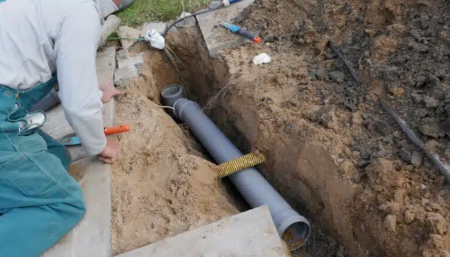 person looking into hole with pipe in ground