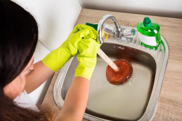 person using plunger on sink