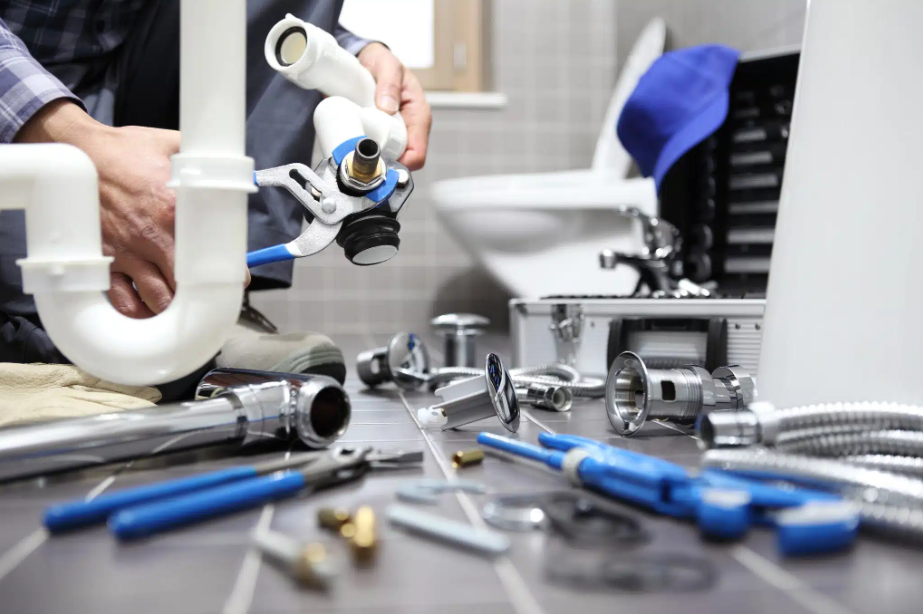 person using wrench on plumbing pipe surrounded by tools
