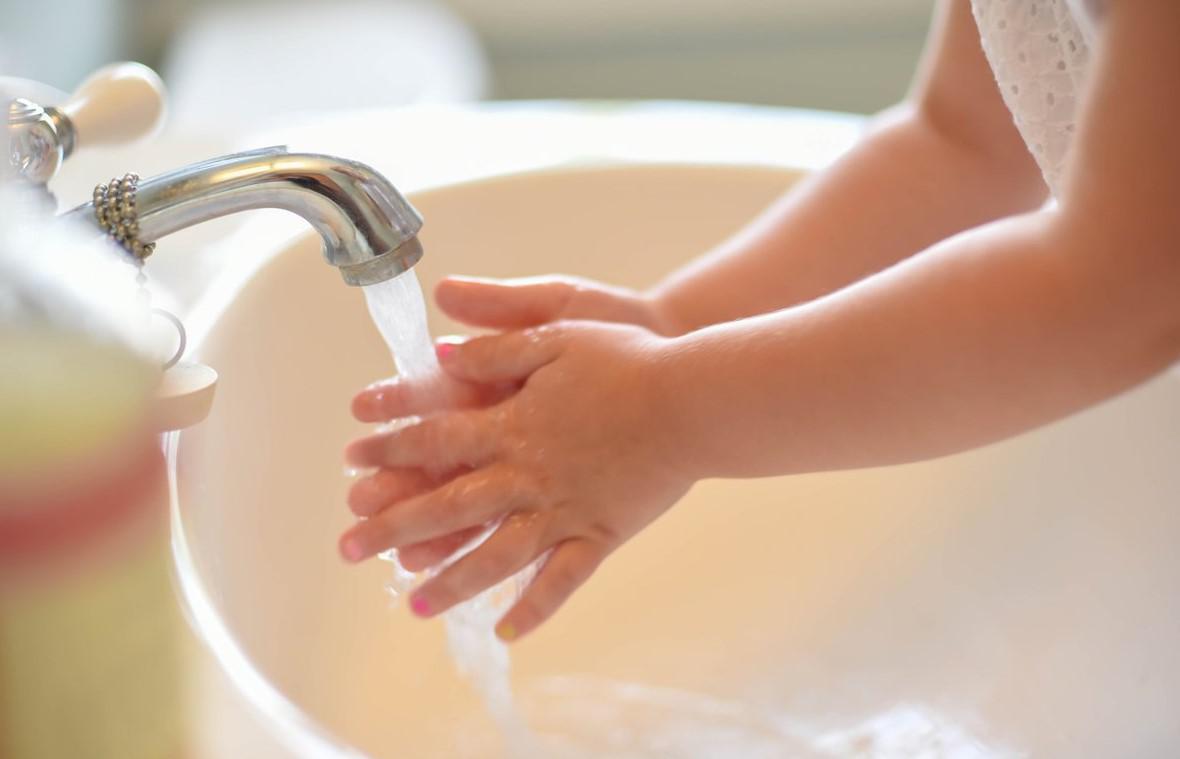 small child washing hands in sink
